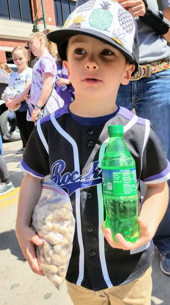 Eli standing outside coors field with a sprite and peanuts