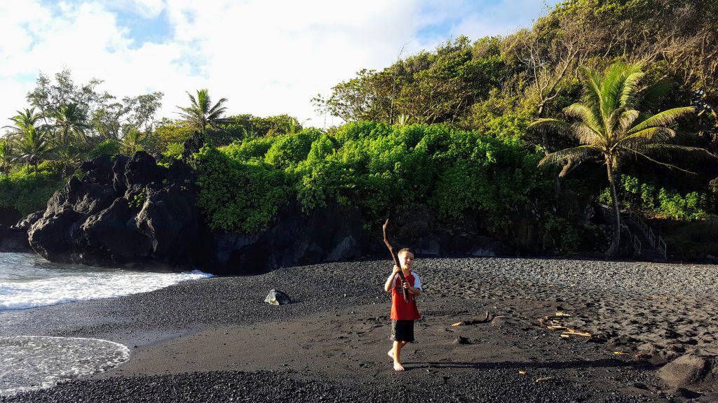 boy on the black sand beach at Wai'anapanapa State Park in Maui, Hawaii