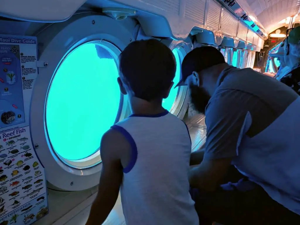 father and son looking out the window in the atlantis submarine tour