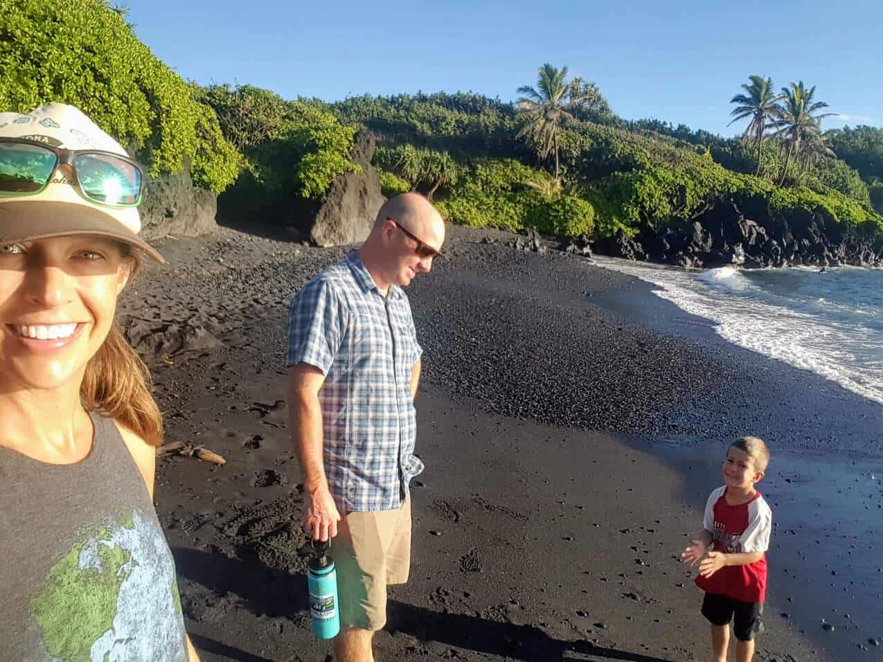 family on the black sand beach on Maui at Waianapanapa State Park Cabins