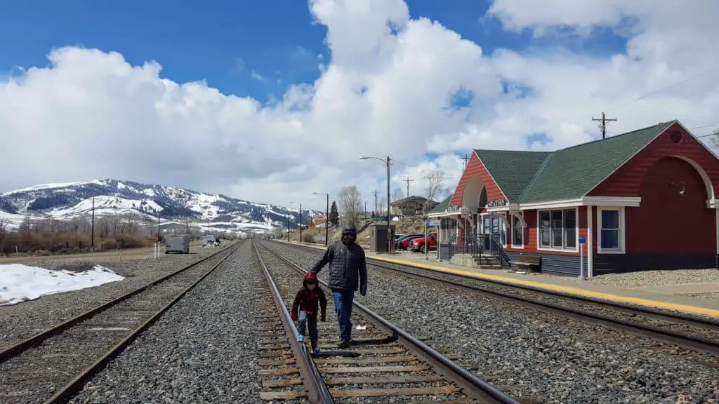 father and son on the train tracks in Colorado with snow covered mountains