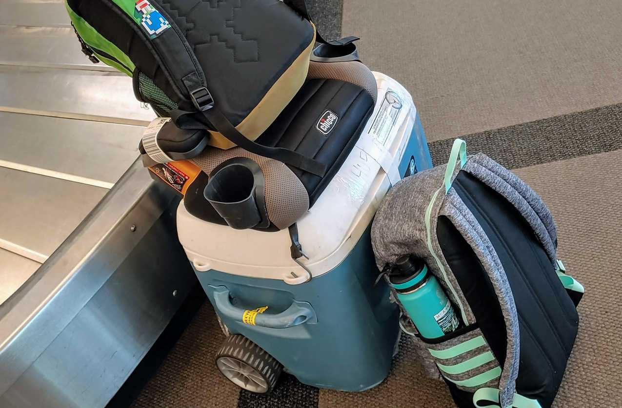 Bags and a cooler next to baggage claim belt