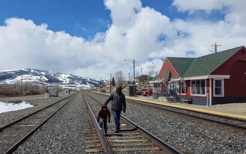 father and son on the train tracks in Colorado with snow covered mountains