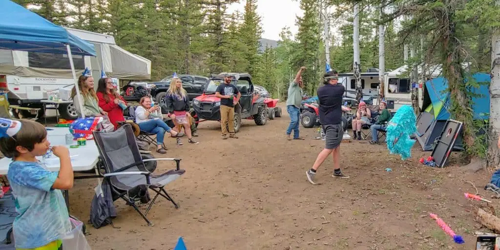 campground with teens hitting a piniata