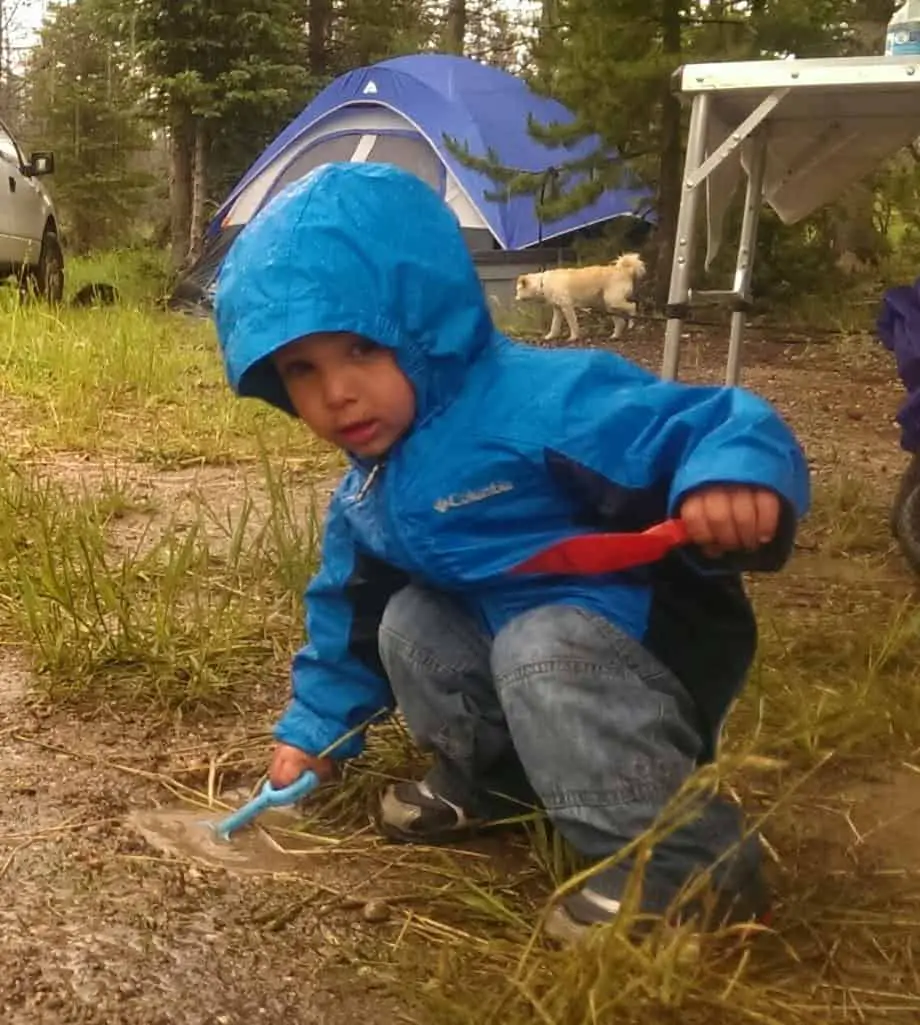 child playing with shovels in the mud