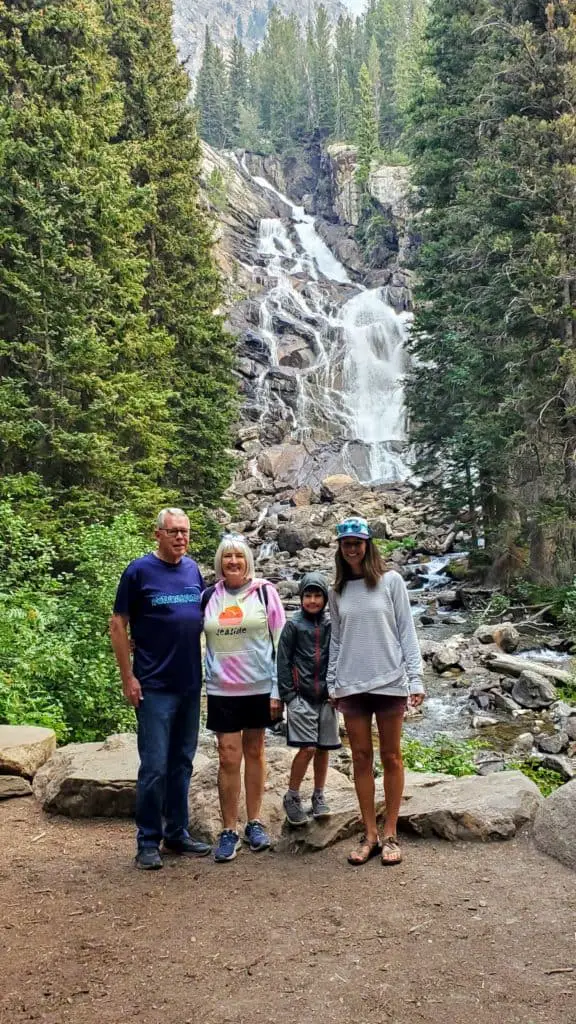 Family standing in front of Hidden Falls in Grand Teton National Park