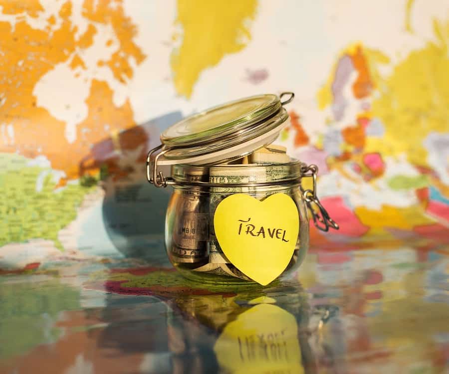 Family Travel On A Budget - Money jar in front of a world map