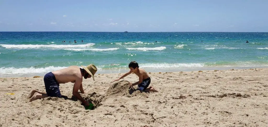 father and son playing in the sand at the beach in Fort Lauderdale
