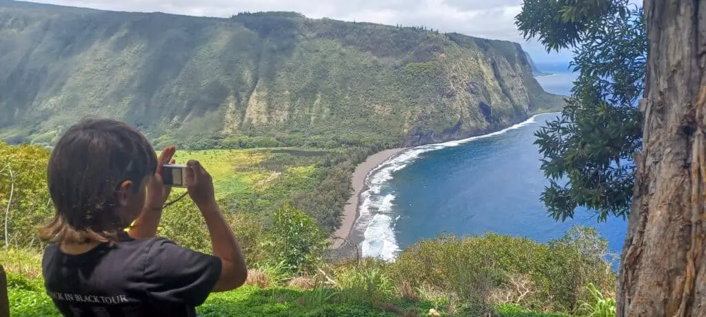 boy taking a picture of Waipio Valley from the overlook on the Big Island of Hawaii