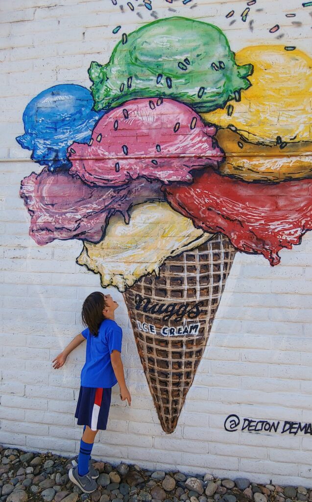 boy pretending to eat ice cream from an ice cream mural painted on a wall in Denver