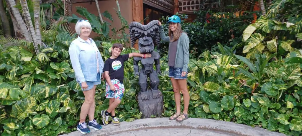 mom, daughter, and grandson in front of a statue at the Polynesian Cultural Center on the island of Oahu