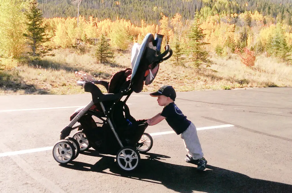 boy pushing his stroller in a parking lot in the mountains