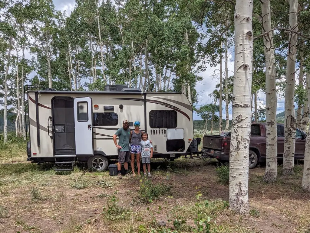 family in front of a camper in the mountains of Utah